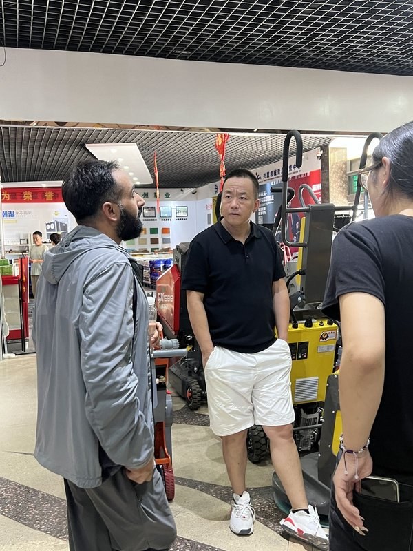 一位外贸人在工厂现场与海外客户交流，背景是真实的生产环境