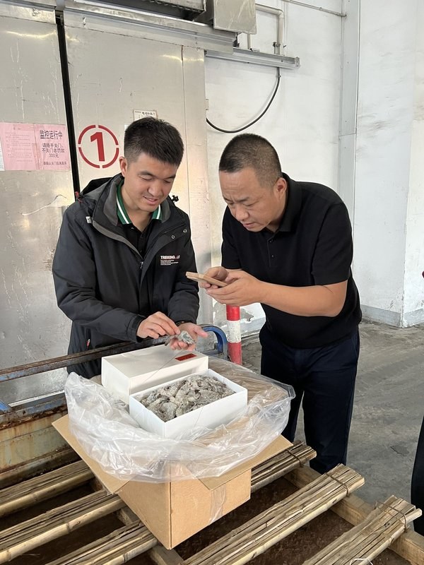 两位外贸从业者在工厂现场查看产品，沟通生产细节