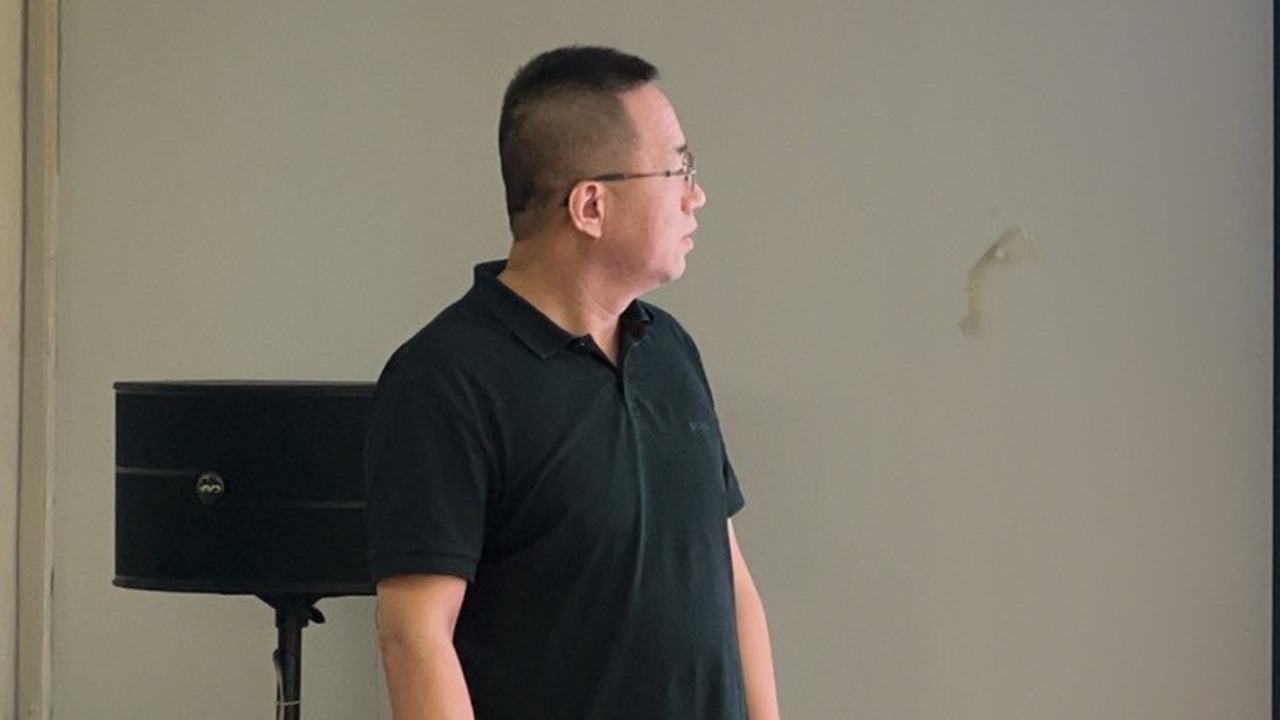 峰哥站在培训教室的讲台旁，面向前方讲解海外客户沟通要点