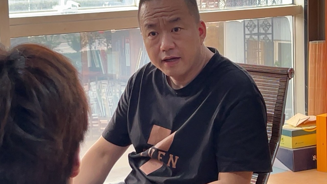 峰哥在明亮的会议室窗边与团队讨论外贸账号矩阵分工