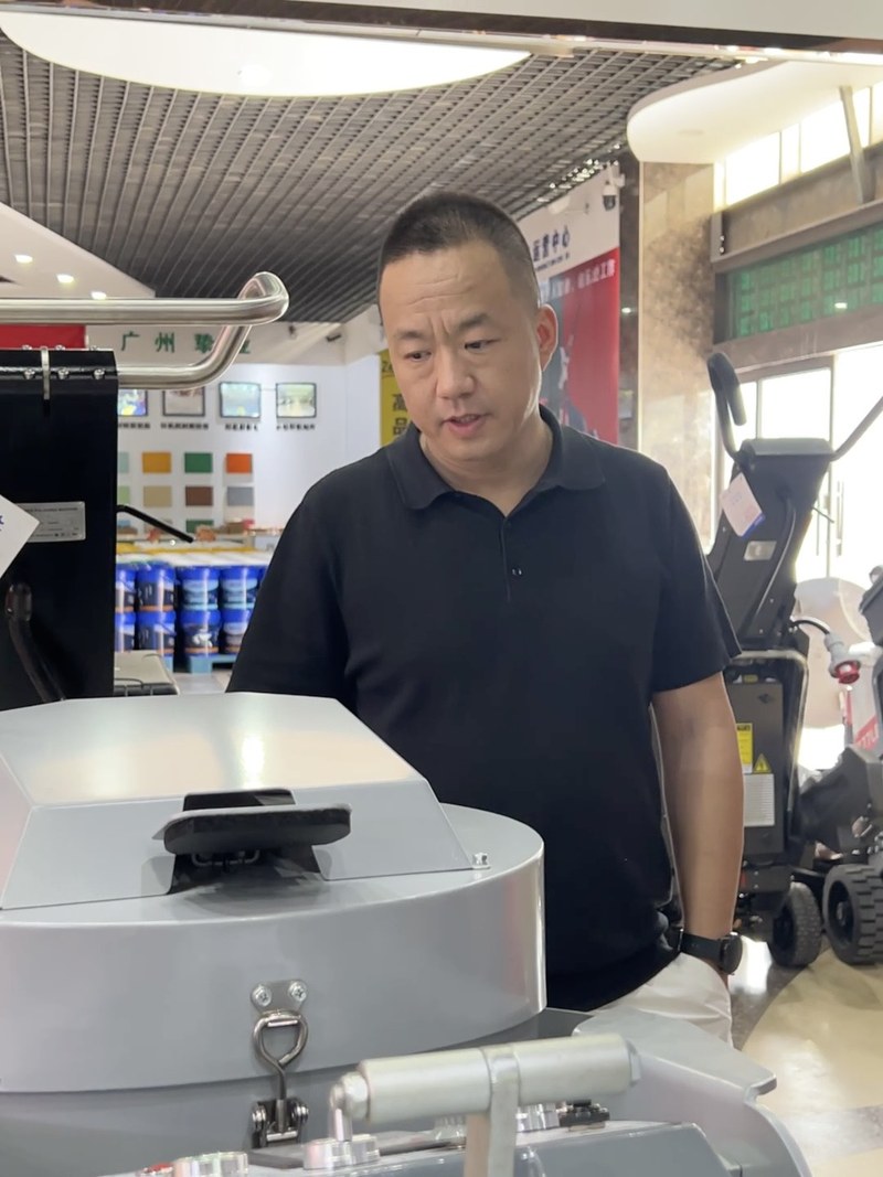外贸人站在展厅研磨机设备前认真查看报名合同条款